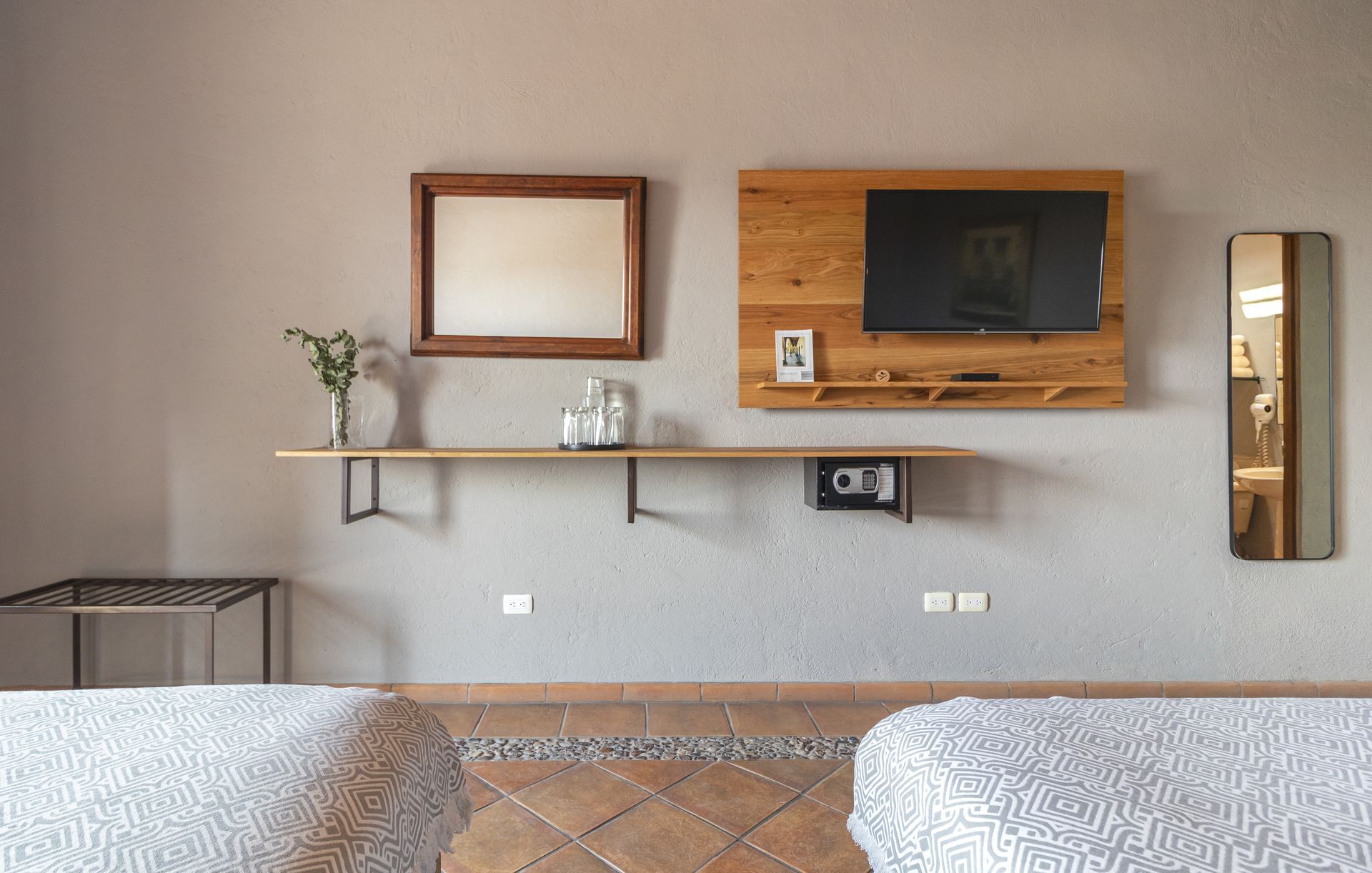 A bedroom with two beds , a television , a mirror and a shelf.