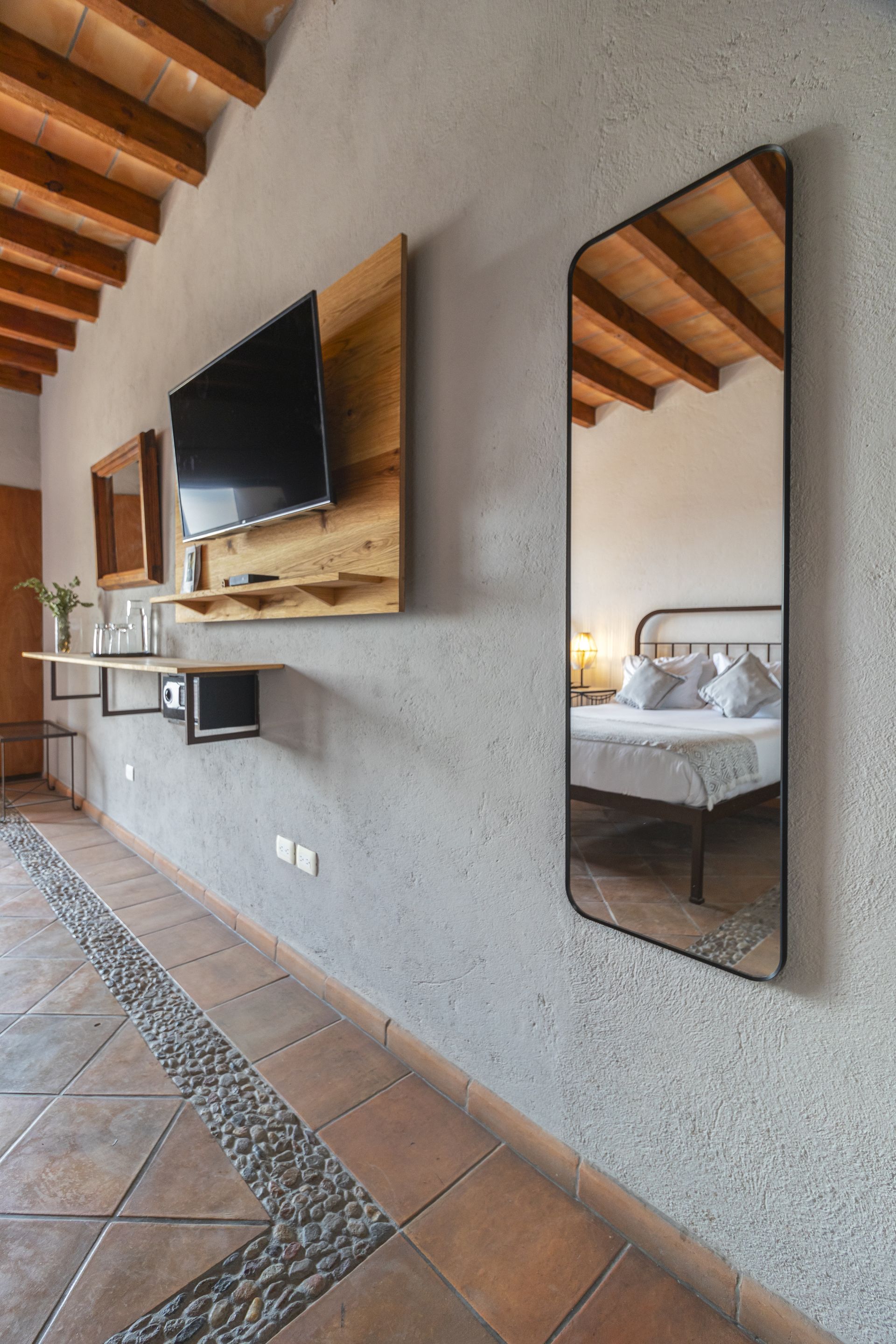 A bedroom with a bed , television , and mirrors on the wall.