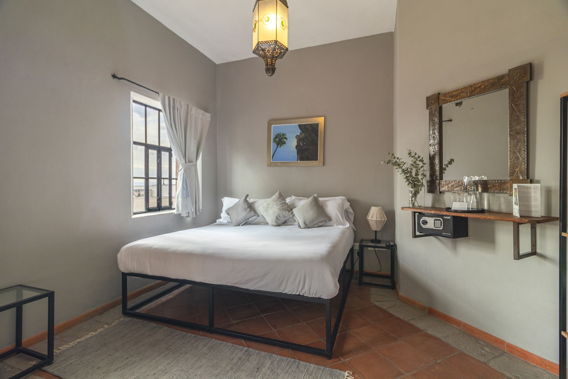 A bedroom with a large bed , a mirror and a window.