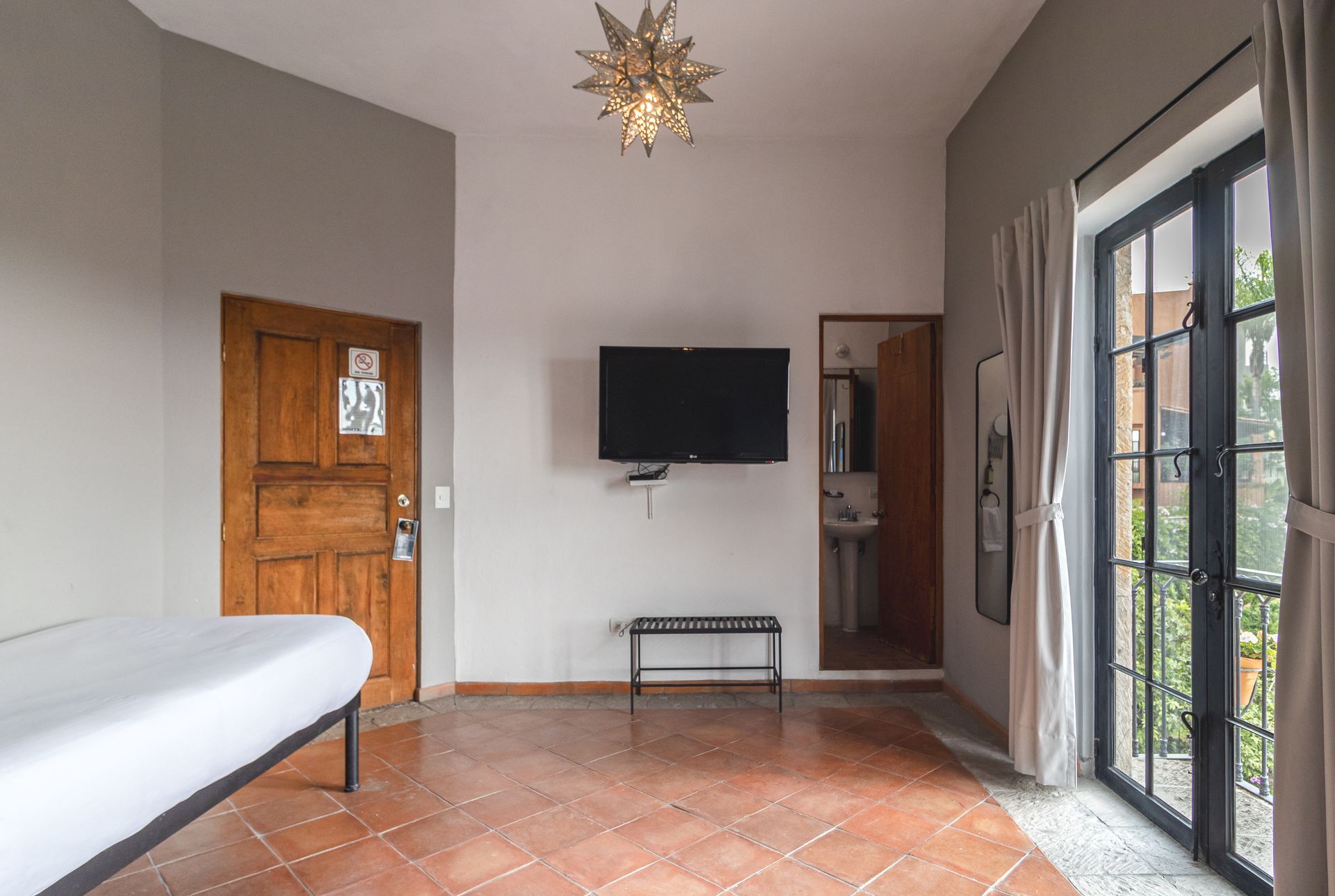 A hotel room with a bed , television , and sliding glass doors.
