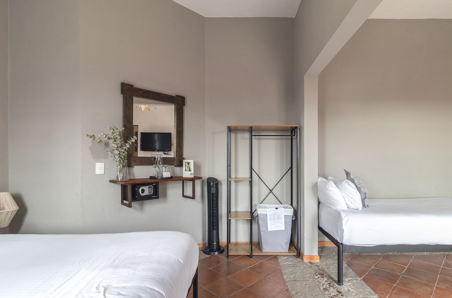 A hotel room with two beds , a mirror and a trash can.