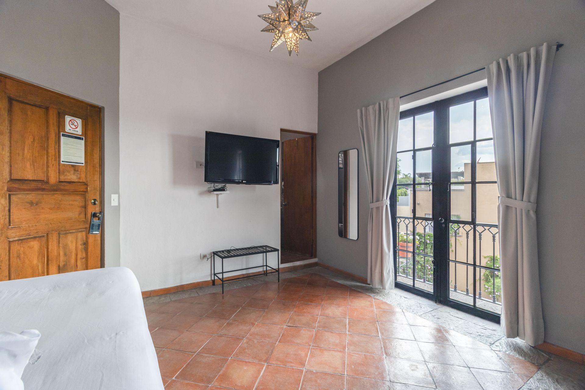 A hotel room with a bed , television , and sliding glass doors.