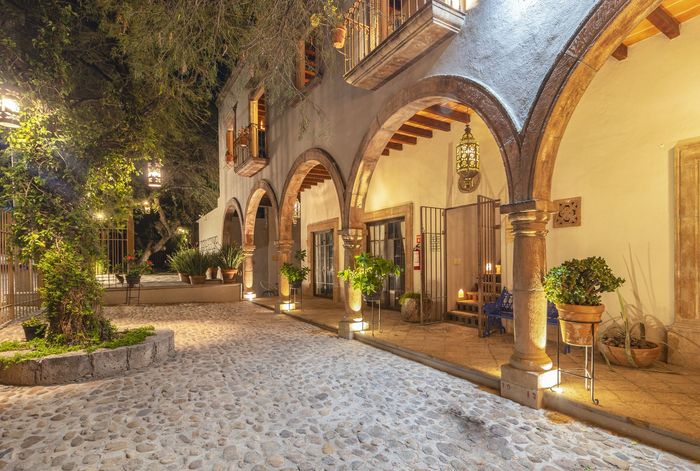 A large building with arches and potted plants in front of it at night.