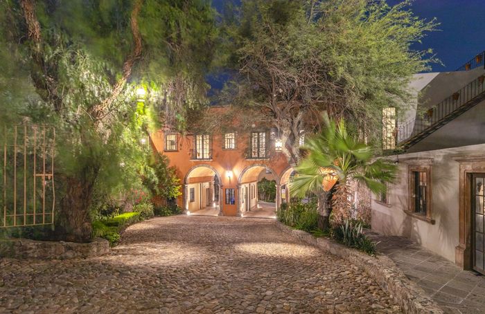 A cobblestone driveway leading to a large building at night.