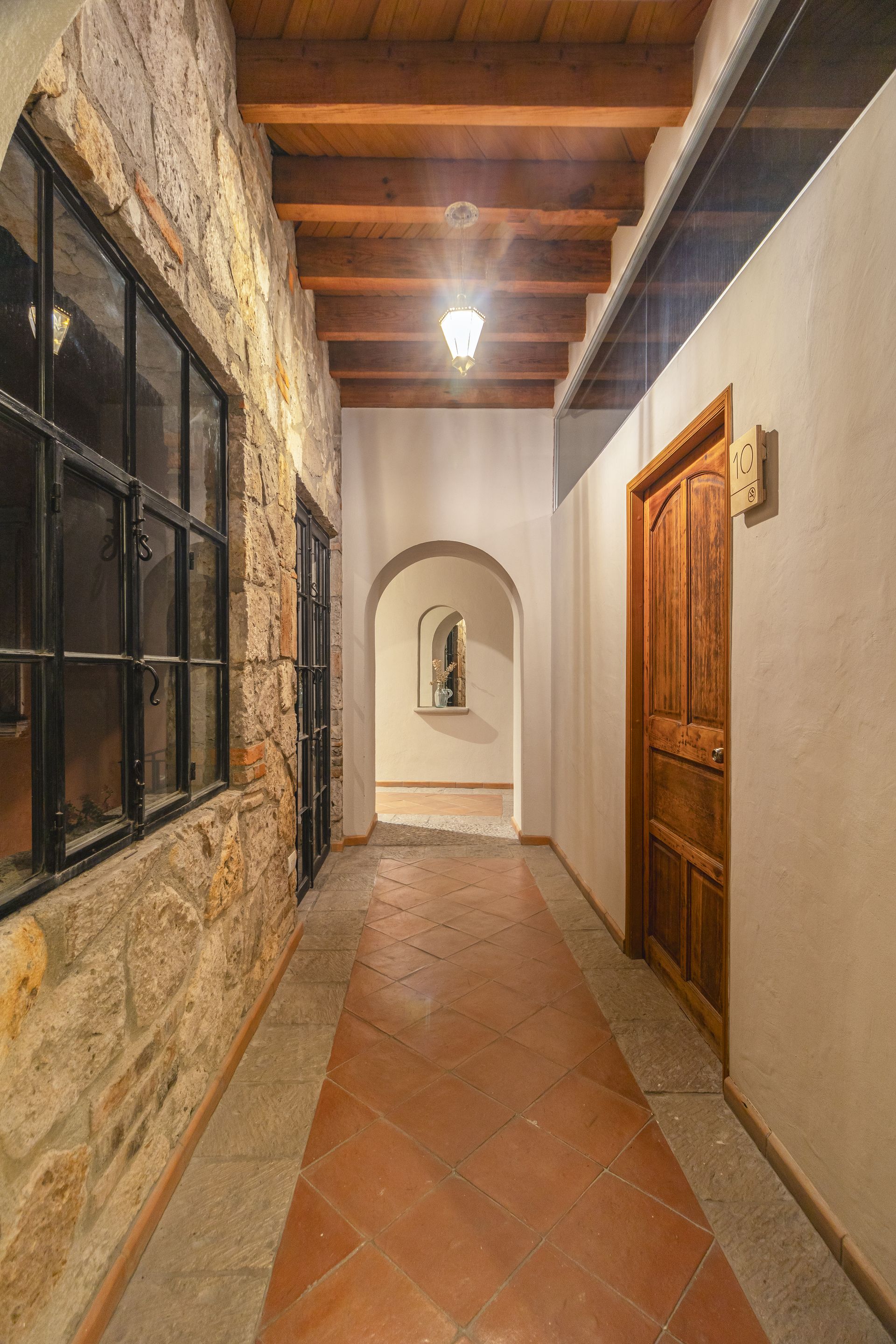 A long hallway with a wooden ceiling and a stone wall.