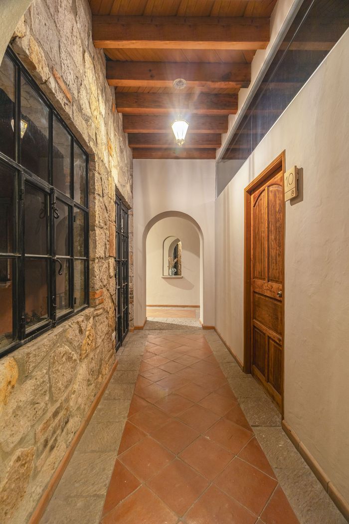 A long hallway with a wooden ceiling and a stone wall.
