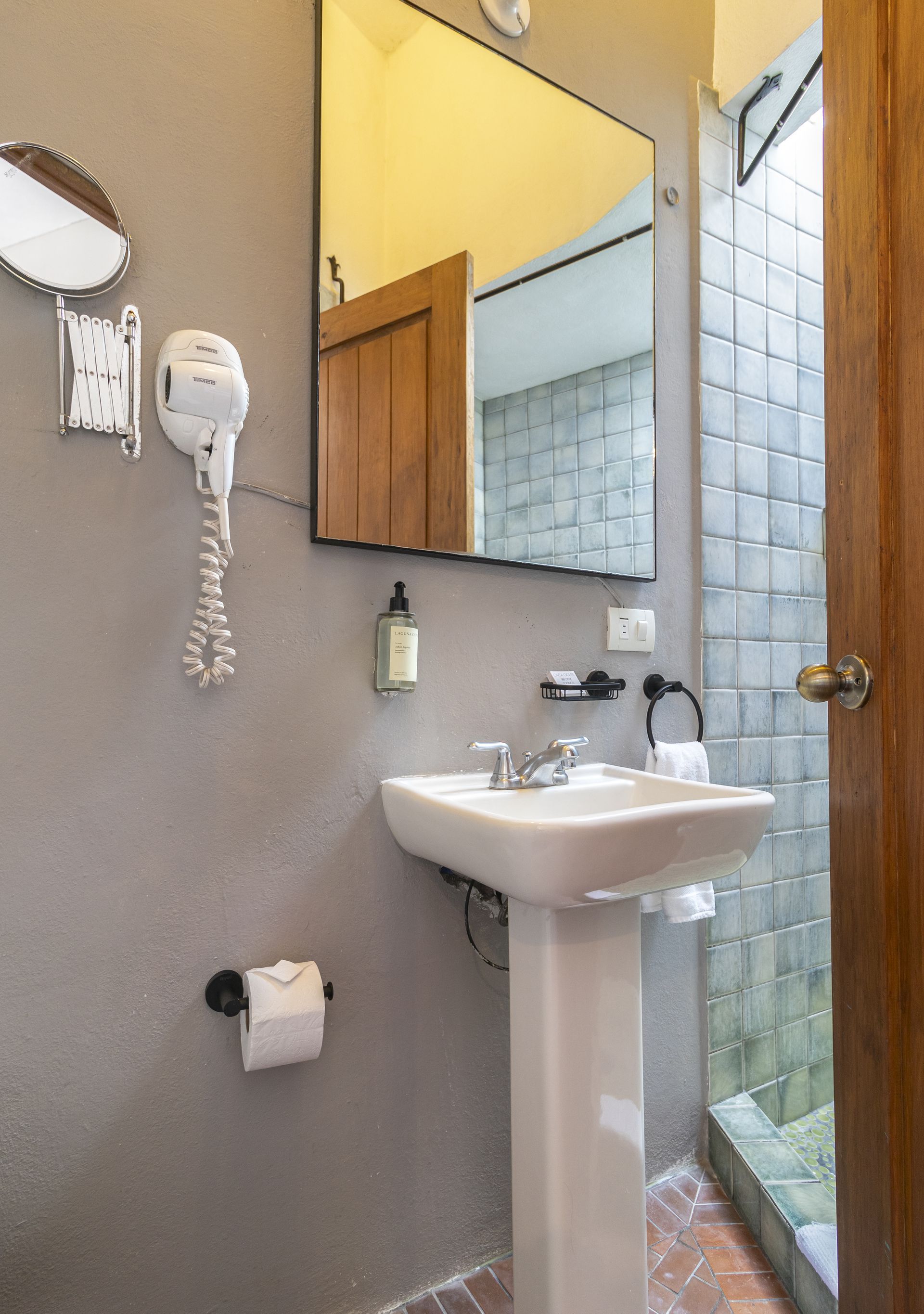 A bathroom with a sink , mirror and hair dryer.
