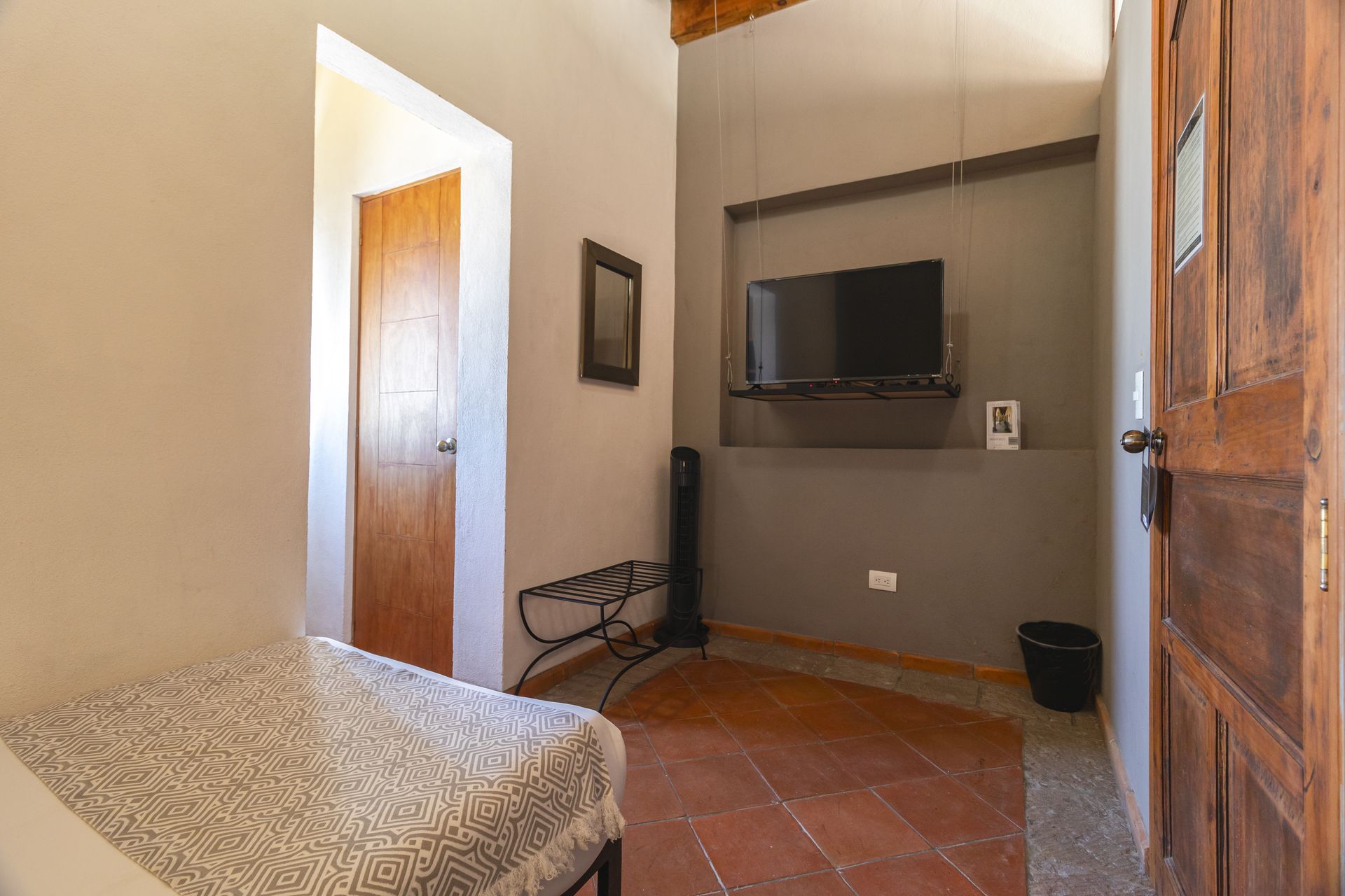 A bedroom with a bed and a television on the wall.