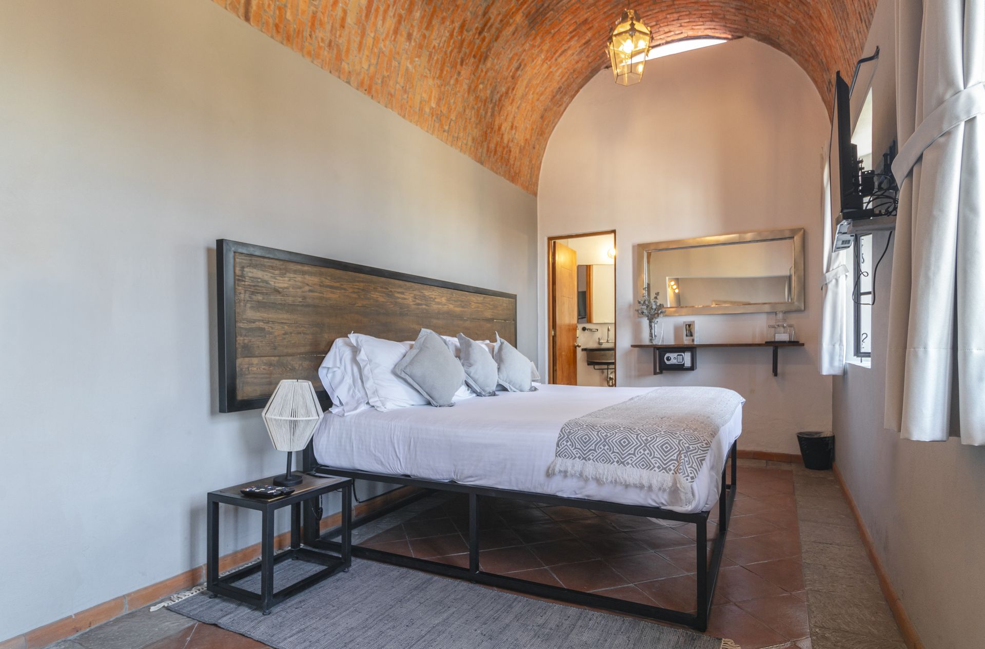 A bedroom with a king size bed and a brick ceiling.