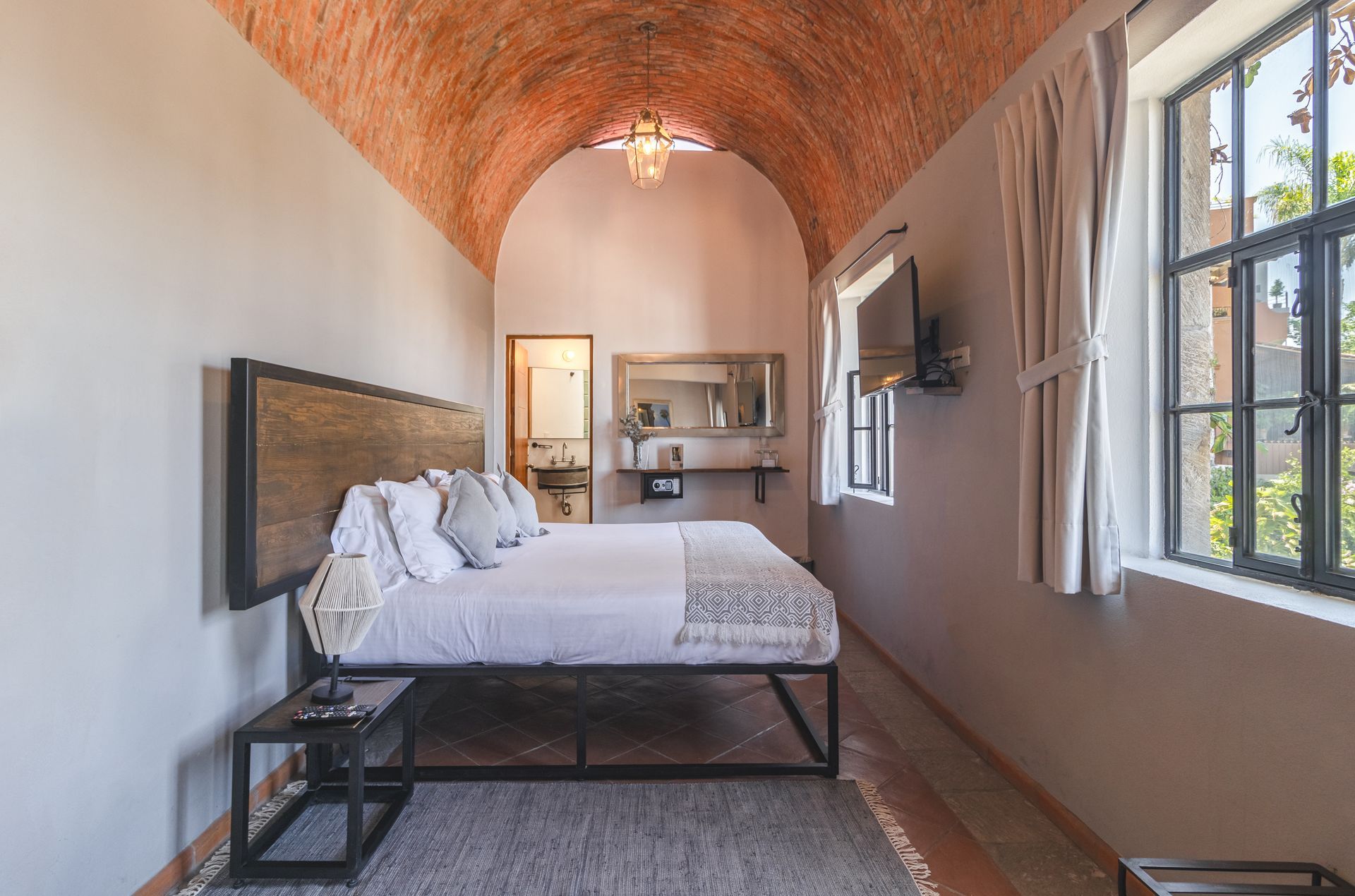 A bedroom with a king size bed and a brick ceiling.