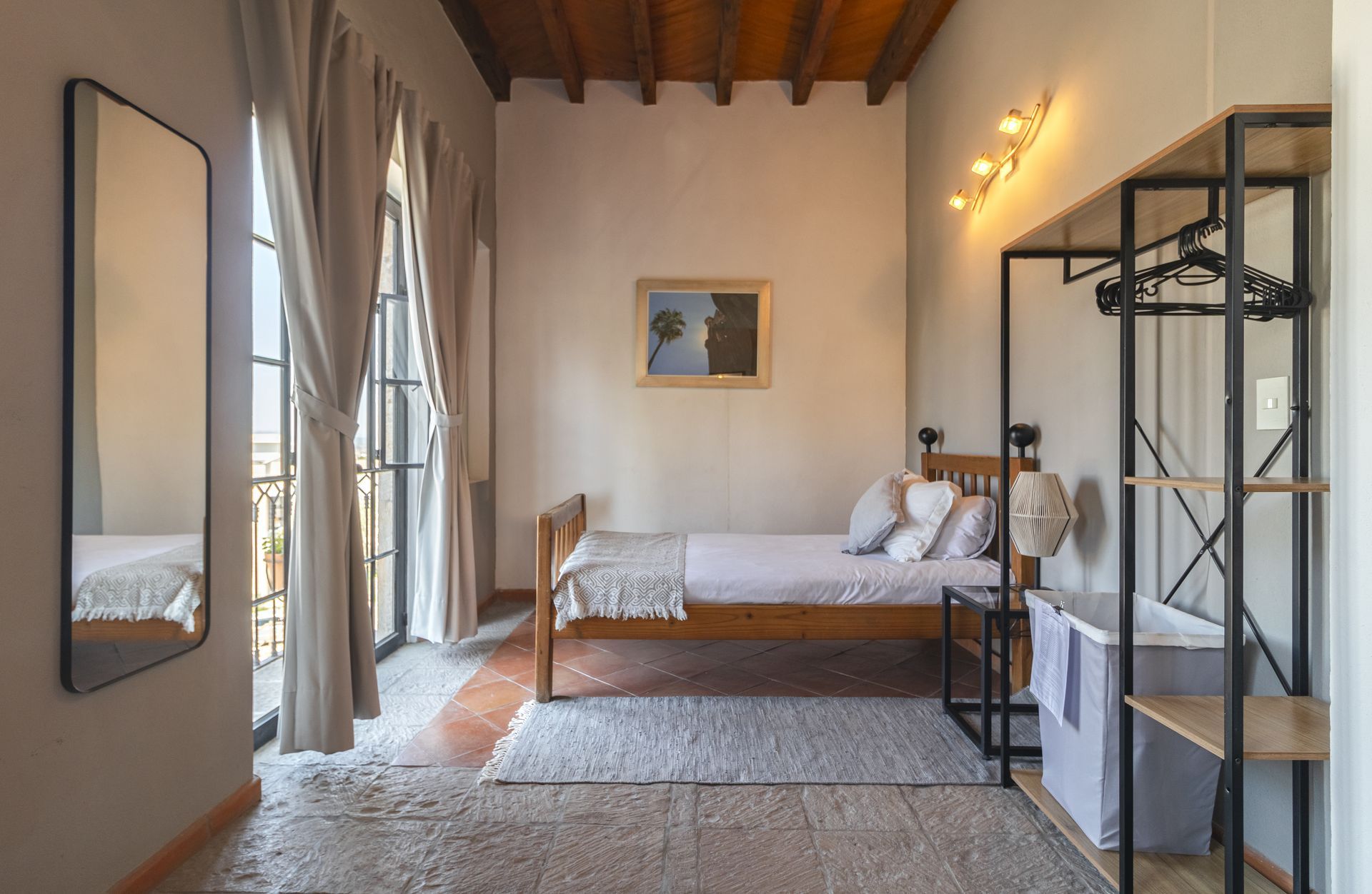 A bedroom with a bed , two mirrors , a closet and a balcony.