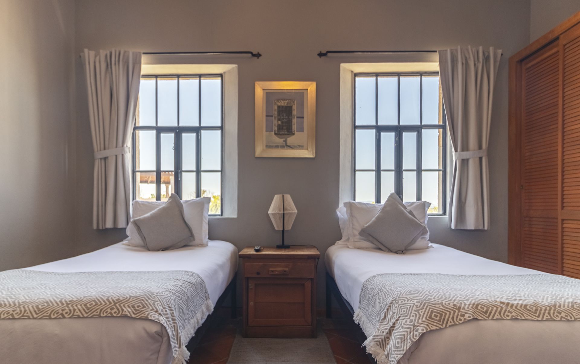A bedroom with two twin beds and two windows.