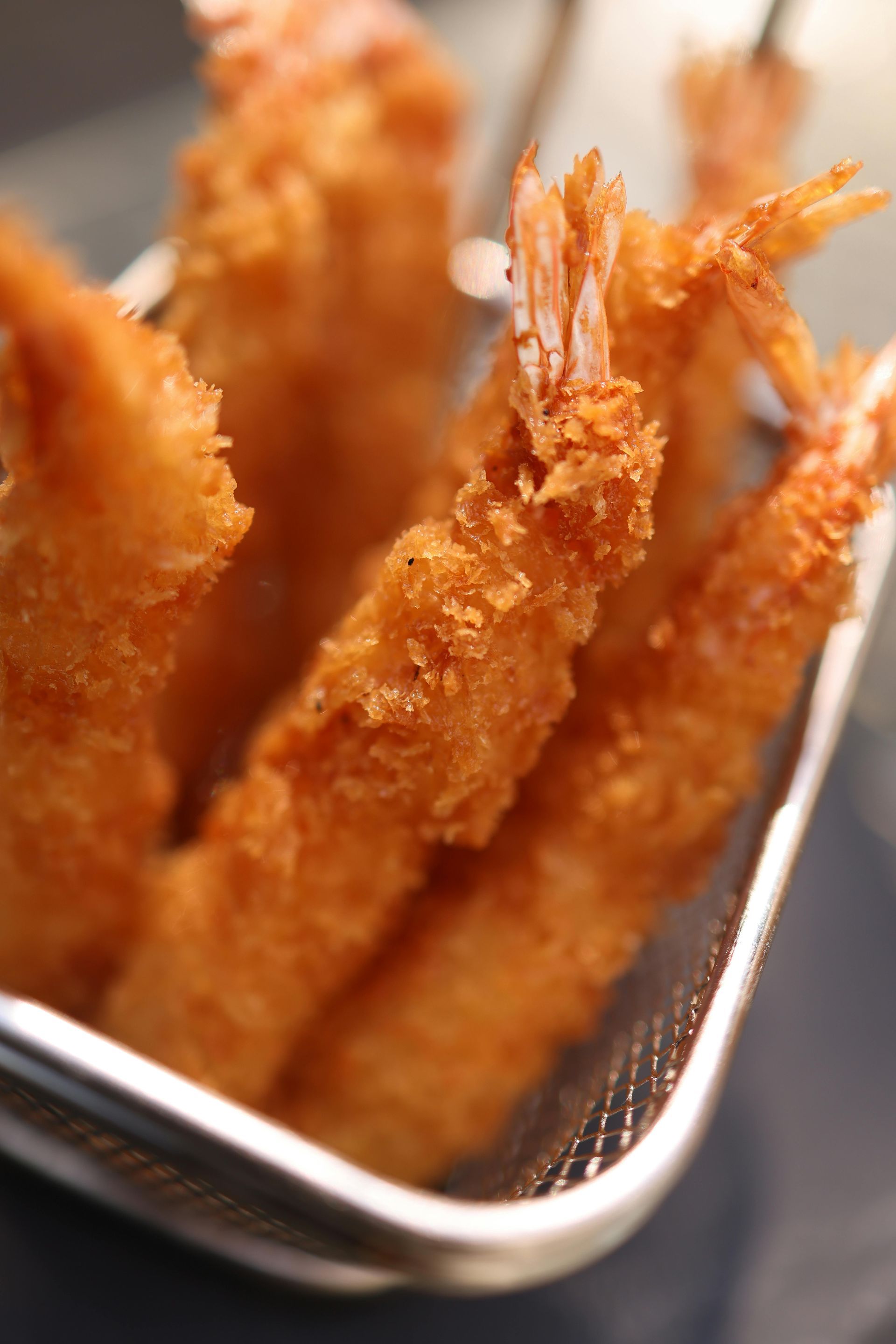 Crispy fried shrimp in a small wire basket.