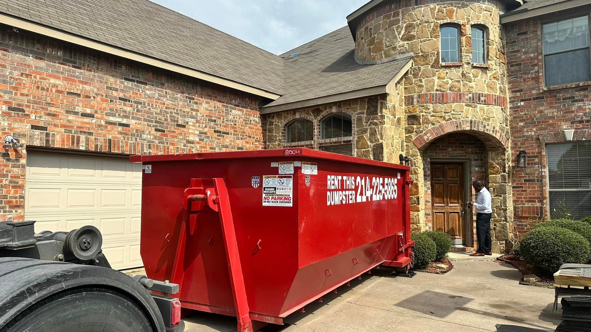 a large red dumpster is parked in front of a large brick house .