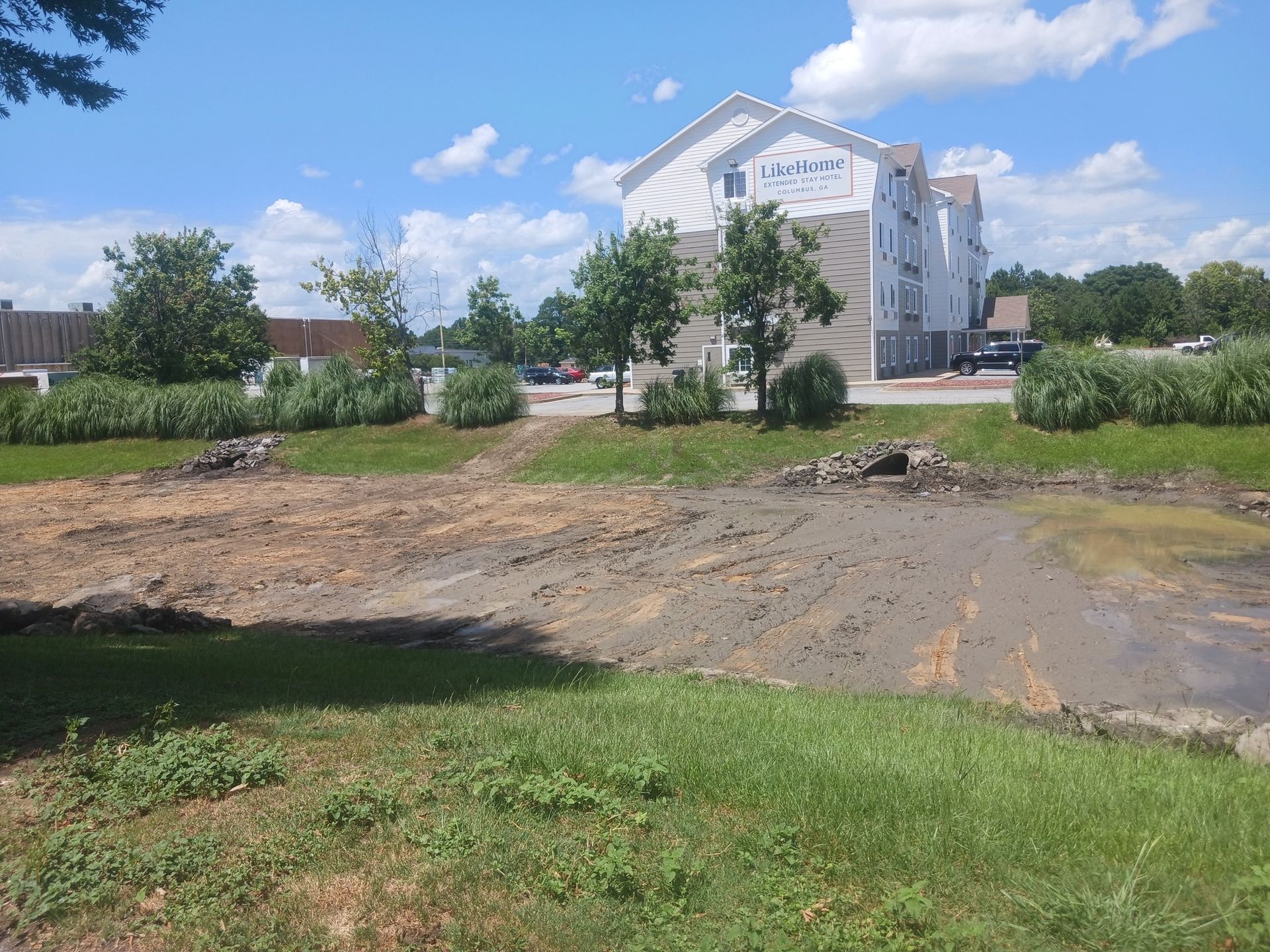 Cleared land in front of a multi-story building on a sunny day.
