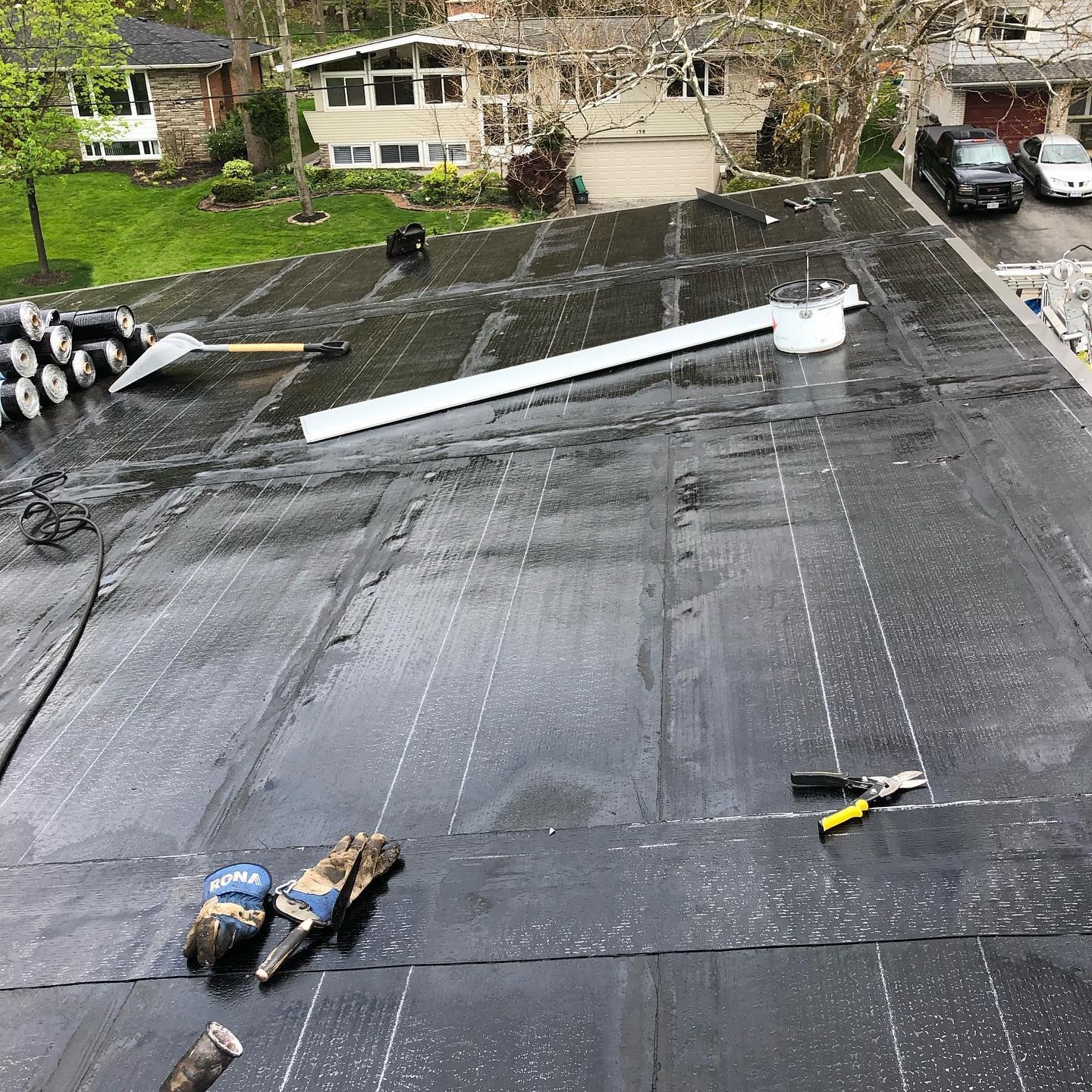 A roof with a lot of tools on it and a house in the background