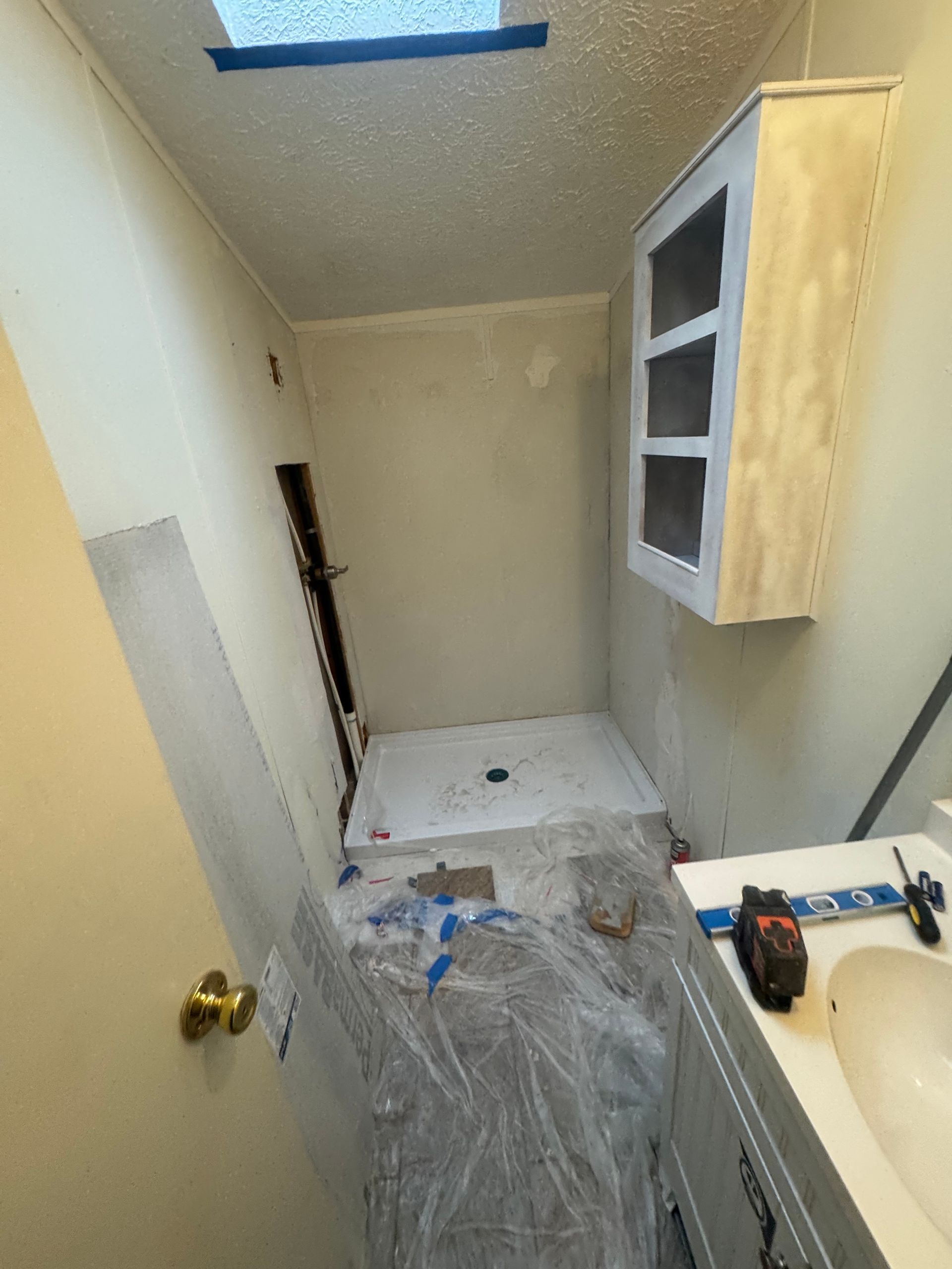 a man is installing tiles on a wall in a bathroom .