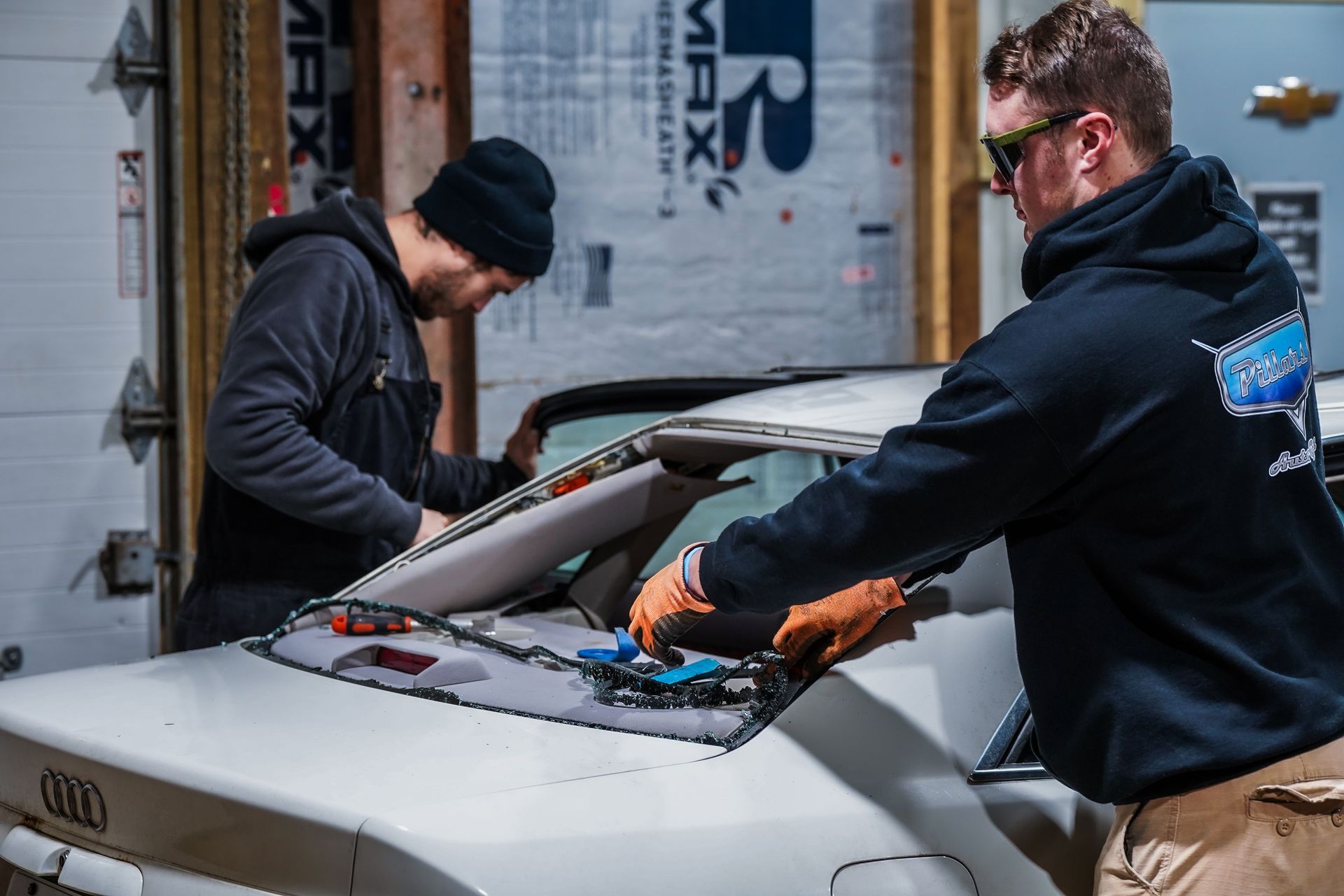 Two men are working on a car in a garage.