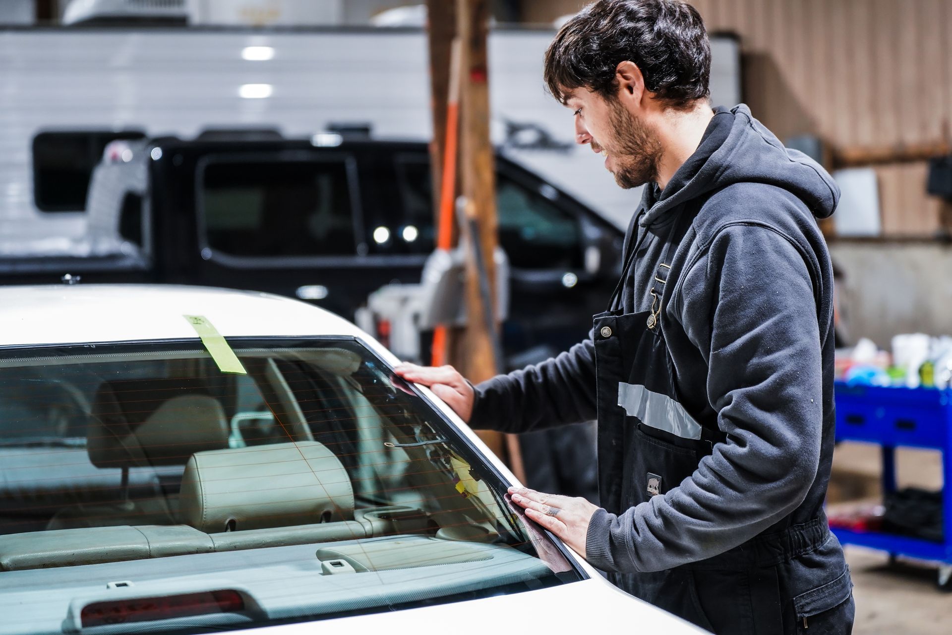 A man is working on a car windshield in a garage.