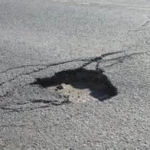Un grand nid-de-poule au milieu d'une route.