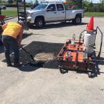 Un homme travaille sur une plaque d'égout dans un parking à côté d'un camion.