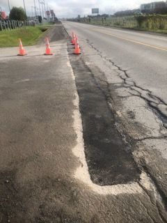 Une rangée de cônes de signalisation orange se trouve sur le bord d'une route.