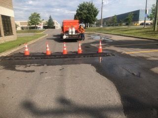 Un camion roule dans une rue à côté d'une rangée de cônes orange.