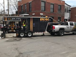 Un camion auquel est attachée une remorque est garé devant un bâtiment en brique.