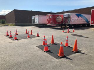 De nombreux cônes de signalisation sont alignés dans un parking.