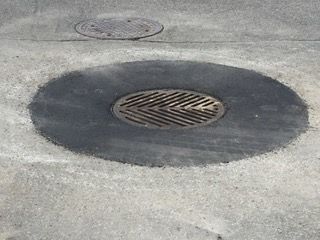 Une plaque d'égout est posée sur le bord d'une route.