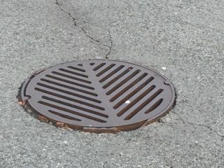 Une plaque d'égout est posée sur le bord d'une route.