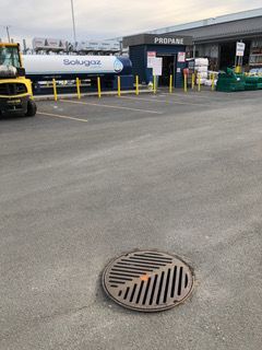 Une plaque d'égout se trouve au milieu d'un parking.