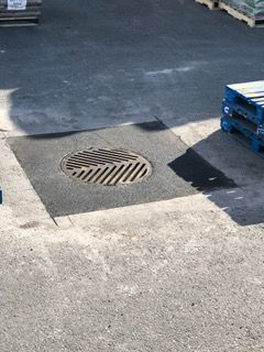 Une plaque d'égout se trouve au milieu d'un parking.