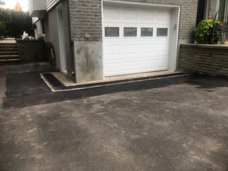 Une porte de garage blanche est ouverte devant une maison en brique.