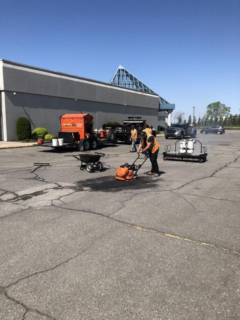 Un groupe de personnes travaille sur un parking devant un immeuble.