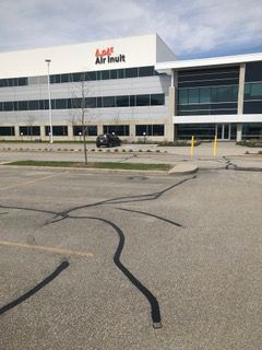 Un grand bâtiment avec beaucoup de fenêtres et un stationnement devant.