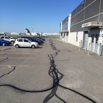 De nombreuses voitures sont garées sur un parking devant un immeuble.