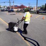 Un homme utilise un aspirateur pour nettoyer un parking.