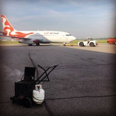 Un avion est stationné sur la piste à côté d'un réservoir de propane.