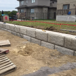 Un mur de pierre est en construction devant une maison.
