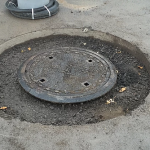Une plaque d'égout est posée au milieu d'un trou dans le sol.