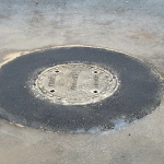 Une plaque d'égout est posée sur une surface en béton.