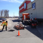 Un homme travaille sur le trottoir devant un immeuble.