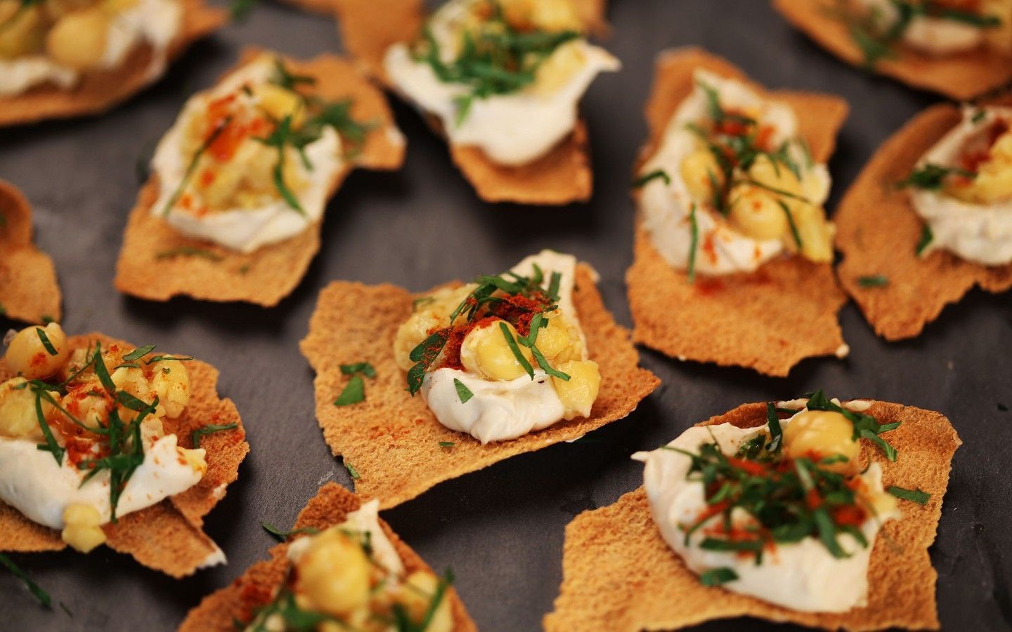 Galletas cubiertas con crema blanca, garbanzos, hierbas y pimentón.