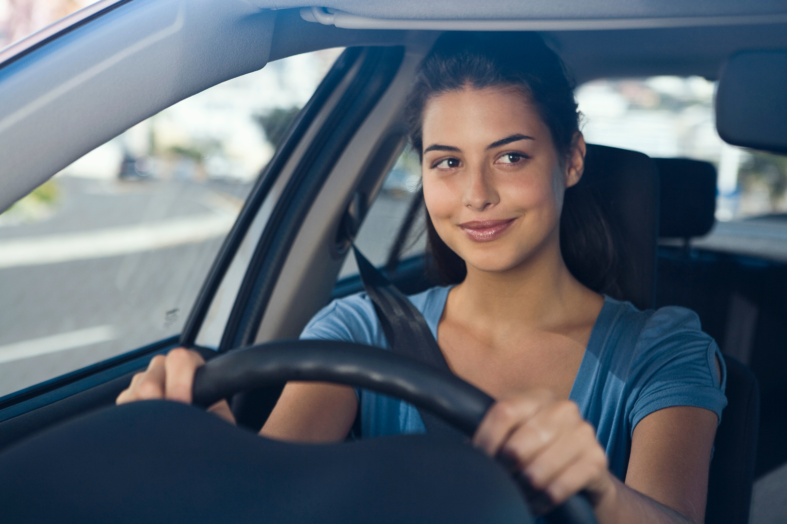 A woman is sitting in the driver 's seat of a car.