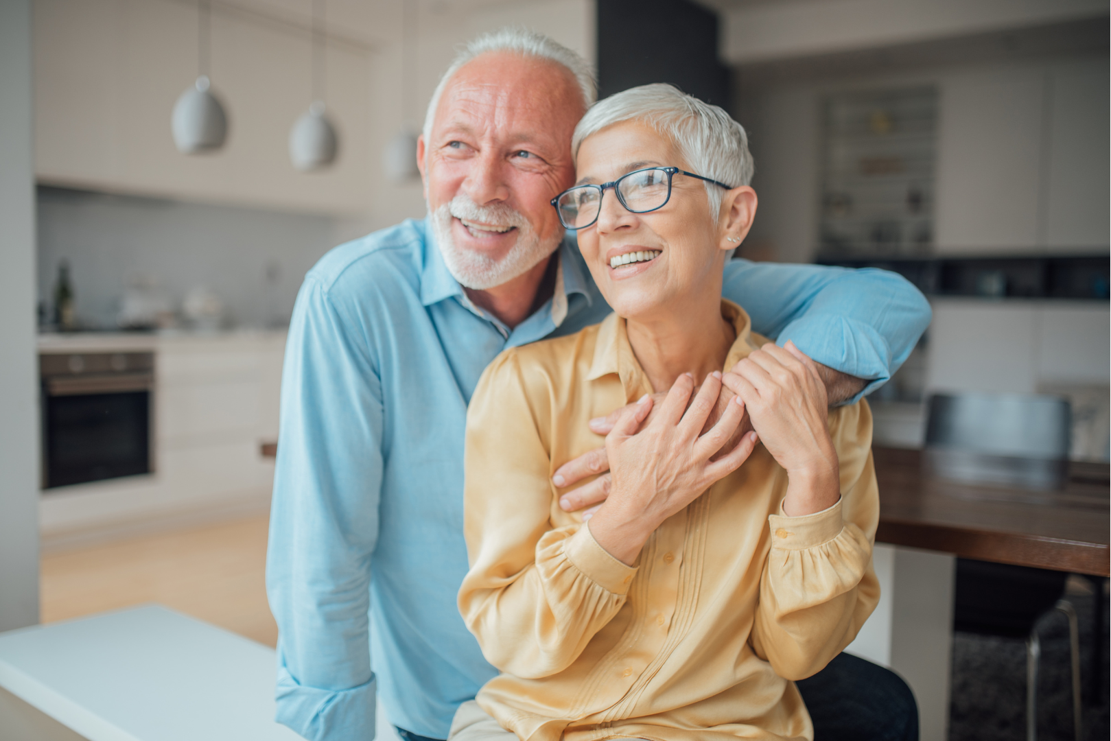 An elderly couple is posing for a picture in a kitchen.