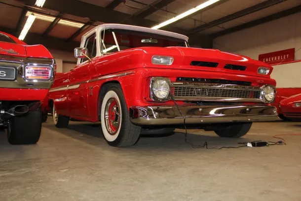 Red classic pickup truck with white roof, parked indoors.