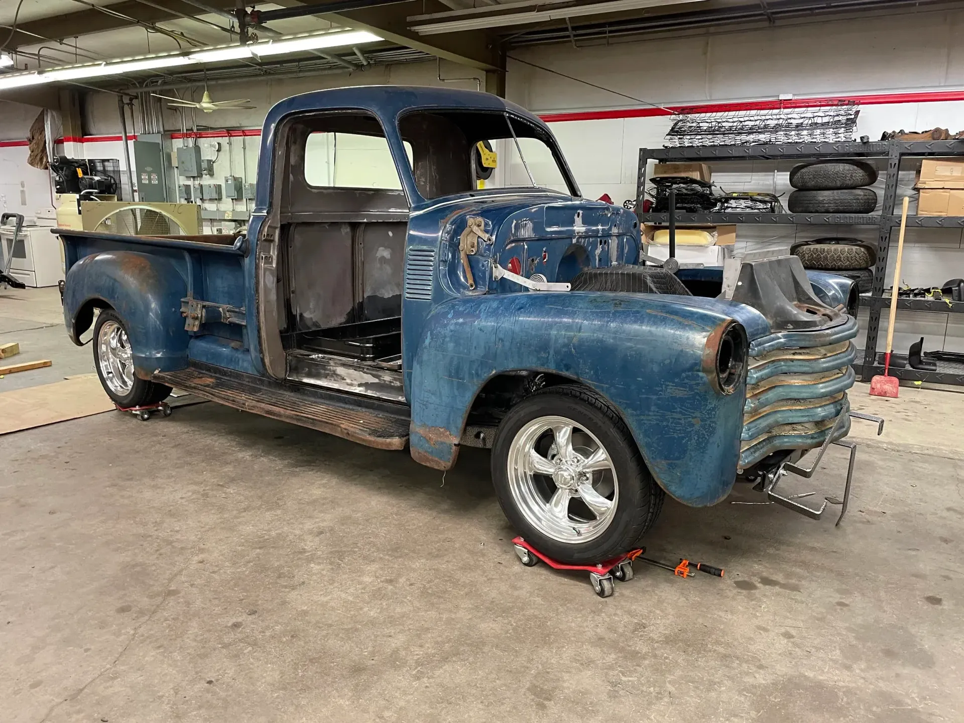 Blue vintage pickup truck in a garage; undergoing restoration.