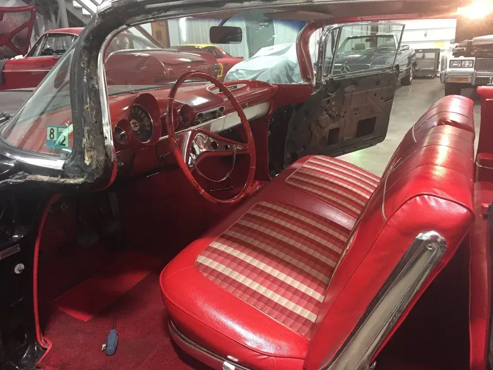 Interior of a classic black car with red seats, dashboard, and steering wheel.