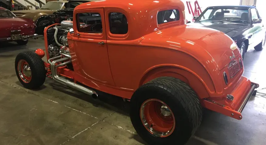 Bright orange vintage hot rod car in a garage.